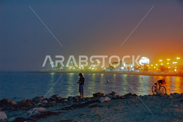 أنشطة ترفيهية ممتعة، الفن الهندسي المعماري للأبنية والمنشآت المضيئة ليلاً، احتراف مهنة الصيد في المملكة العربية السعودية، منتجات وطنية محلية، رجل عربي خليجي سعودي يمارس صيد السمك على شاطئ الخليج العربي