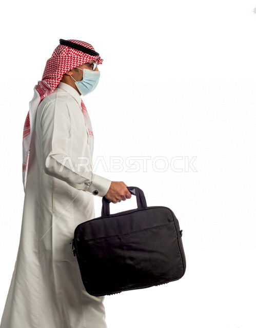 بورتريه لرجل أعمال خليجي سعودي يحمل حقيبة للذهاب إلى العمل بإيماءات وجه ويدين مختلفة، مرتدي القناع الطبي الوقائي للوقاية من فايروس كورونا كوفيد-19، منظر جانبي لرجل سعودي بالزي التقليدي السعودي، إتباع إجراءات الوقاية من الفايروسات، الحفاظ على المسافات
