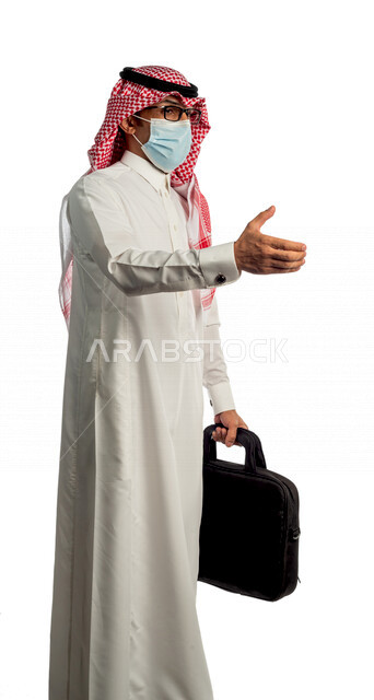 بورتريه لرجل أعمال خليجي سعودي يحمل حقيبة، يشير بيده للمصافحة بإيماءات يدين مختلفة، مرتدي القناع الطبي الوقائي للوقاية من فايروس كورونا كوفيد-19، منظر جانبي لرجل سعودي بالزي التقليدي السعودي، إتباع إجراءات الوقاية من الفايروسات، الحفاظ على المسافات