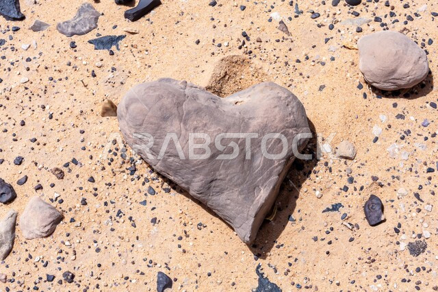 حجر بركاني أسود على شكل قلب في صحراء مدينة الرياض بالمملكة العربية السعودية، الآثار الطبيعية المتواجدة في الصحاري على مر آلاف السنين، علم الجيولوجيا والأرض، الطبيعة الجافة والبيئة القاحلة، الرمال الذهبية الناعمة في المناطق الصحراوية