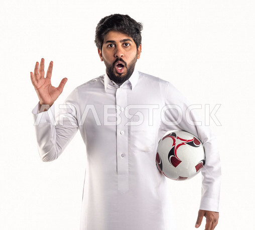 بورتريه لشاب عربي خليجي سعودي يحمل كرة قدم تحت ذراعه، تشجيع فريق كرة قدم، إيماءات وجه ويدين تدل على الدهشة والخذلان، خلفية بيضاء