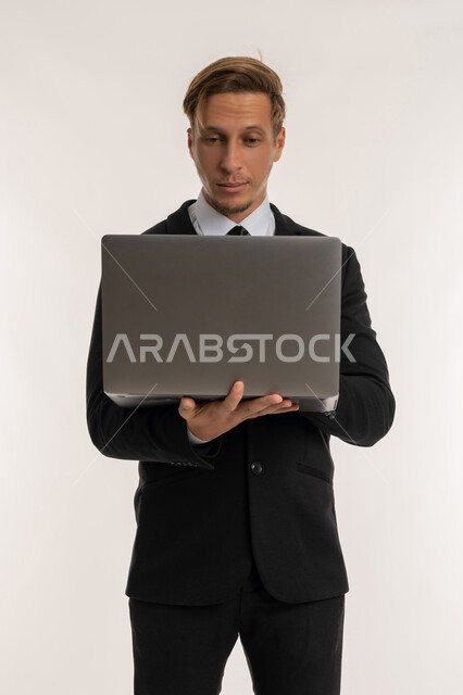 دمج التكنولوجيا في الحياة العملية، إدارة شؤون الأعمال وتنظيمها، استخدام التقنيات الحديثة المتطورة، عقد إجتماع عمل عبر الإنترنت، بورتريه لرجل اعمال اجنبي يرتدي البدلة الرسمية يقوم بالعمل على الحاسب المحمول، النقر والتفاعل مع لوحة المفاتيح، خلفية بيضاء