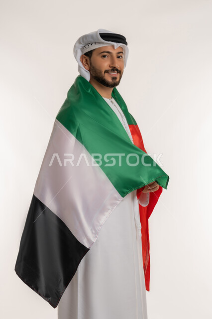 احياء ذكرى استقلال الإمارات 1971، بورتريه من الجانب لرجل عربي خليجي إماراتي يرتدي الكندورة والغترة يحمل علم الإمارات على ظهره، الحب والانتماء للوطن، النظر الى الكاميرا بايماءات الاعتزاز والثقة، هوية اليوم الوطني الاماراتي 2  ديسمبر، اخلفية بيضاء