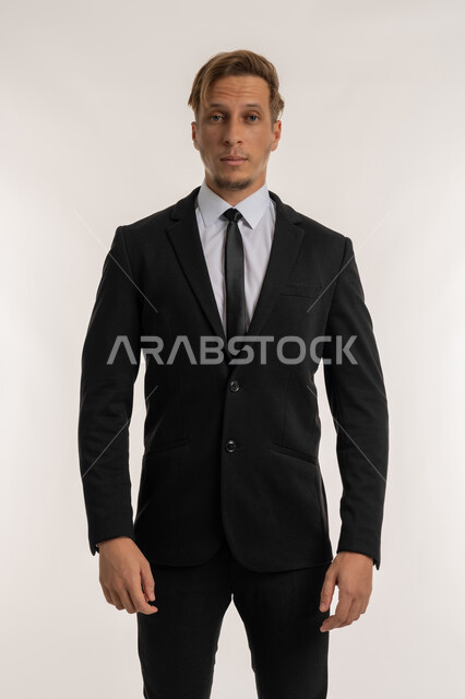 الوقوف باستقامة بايماءات الثقة بالنفس, مفهوم الاناقة والرجولة, بورتريه لرجل أعمال أجنبي يرتدي البدلة الرسمية ينظر الى الكامير بتعابير الجدية والحزم, الاهتمام بالمظهر الخارجي، التقاط صورة شخصية للوثائق الرسمية, خلفية بيضاء