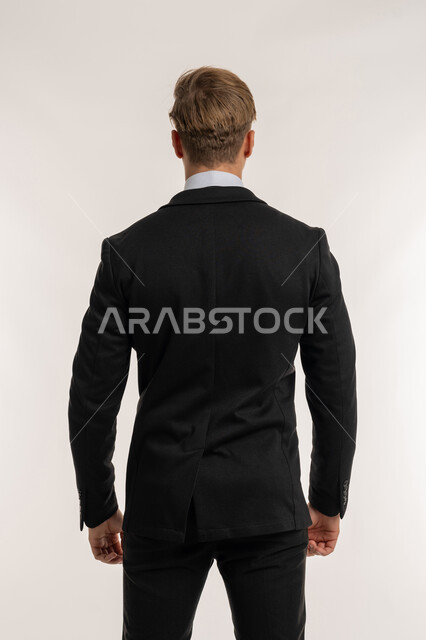 Objection to a specific topic, concept of masculinity and strength, elegance and interest in appearance, portrait from the back of a foreign man in a formal suit looking at something, standing straight and steady, white background