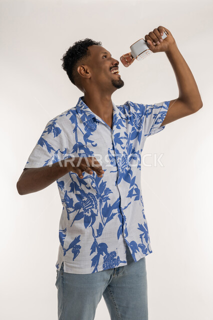 ايماءات السعادة والاندماج، قضاء وقت ممتع بأداء العروض الصوتية، رجل سعودي يقوم بتسجيل مقطع صوتي غنائي، تقديم الفقرات والبرامج الفنية الترفيهية، بورتريه لرجل عربي اماراتي خليجي يرتدي الزي الكاجوال يمسك بيده المايك  ويغني بحماس، خلفية بيضاء