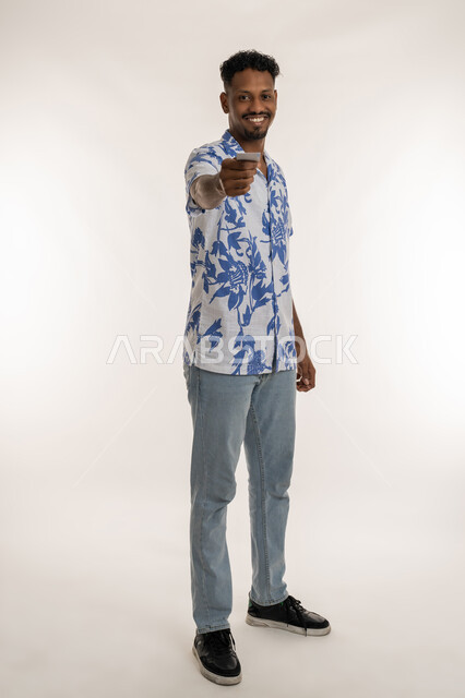 النظر الى الكاميرا بتعابير الفرح والسرور، توضيح أهمية الهوية الشخصية، شاب سعودي يحمل بيده كرت فارغ مستطيل الشكل، بورتريه لرجل عربي خليجي اماراتي مبتسم يرتدي الزي الكاجوال يقوم بتقديم موك اب ابيض, صورة الجسم بالكامل، خلفية بيضاء