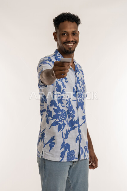 Illustration of the importance of personal identity, a young Saudi man holding a blank rectangular card, portrait of a smiling Arab Gulf Emirati man wearing casual clothes presenting a white mockup, white background