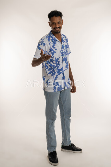 إلقاء التحيه والسلام, مفهوم الاستقبال والترحيب، بورتريه لرجل عربي خليجي إماراتي مبتسم يرتدي الالزي الكاجوال ينظر الى الكاميرا يمد يده بإيماءات المصافحة، اشاب سعودي يقوم بتكوين صداقة وعلاقة جديدة, صورة الجسم بالطول الكامل، خلفية بيضاء