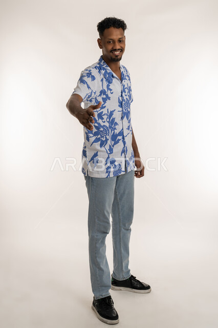 مفهوم الاستقبال والترحيب، بورتريه لرجل عربي خليجي إماراتي مبتسم يرتدي الزي الكاجوال يمد يده بإيماءات المصافحة، شاب سعودي يقوم بالقاء التحية، التعارف و الصداقه وتكوين العلاقات, صورة الجسم بالطول الكامل، خلفية بيضاء