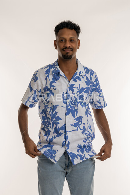 الحاجة للمال والمساعدة، مفهوم الافلاس وعدم امتلاك الأموال، رجل سعودي ينظر إلى الكاميرا بتعابير الحزن والاكتئاب، بورتريه لشاب اسمر عربي خليجي اماراتي يرتدي الزي الكاجوال يقوم بسحب جيب بنطاله للخارج بايماءات الفقر, خلفية بيضاء