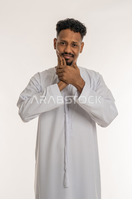 ضرورة الذهاب للطبيب والحصول على العلاج, بورتريه لشاب عربي خليجي إماراتي يرتدي الكندورة يضع يده على وجهه بإيماءات الألم ووجع الأسنان، مفهوم تسوس الأضراس، الإنتفاخ والإلتهاب بالفم واللثة، خلفية بيضاء