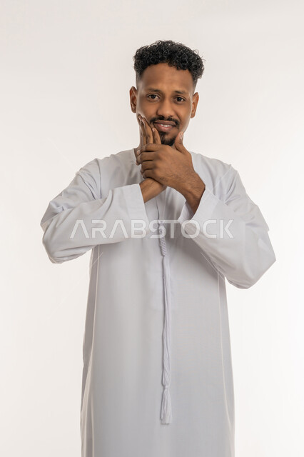 الإنتفاخ والإلتهاب بالفم واللثة، ضرورة الذهاب للطبيب والحصول على العلاج, بورتريه لشاب عربي خليجي إماراتي يرتدي الكندورة يضع يده على وجهه بإيماءات الألم ووجع الأسنان، مفهوم تسوس الأضراس، خلفية بيضاء