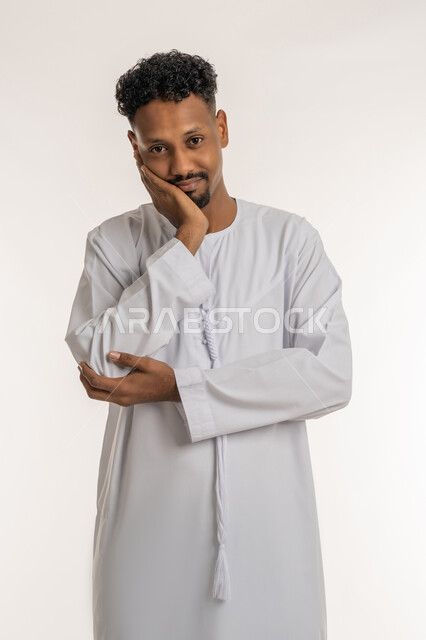 الإنتفاخ والإلتهاب بالفم واللثة، مفهوم تسوس الأضراس, بورتريه لشاب عربي خليجي إماراتي يرتدي الكندوره يضع يده على وجهه بإيماءات الألم ووجع الأسنان، ضرورة الذهاب للطبيب والحصول على العلاج، خلفية بيضاء