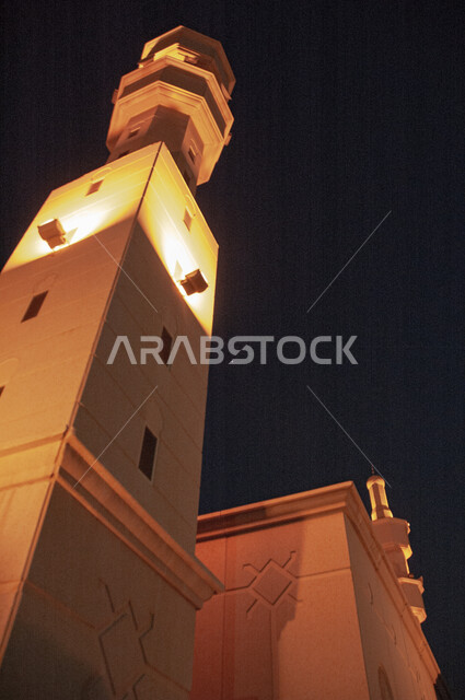 Illuminated minaret of a mosque at night in the Kingdom of Saudi Arabia, the concept of worship and drawing closer to God Almighty, the call of Muslims to perform religious duties and acts of worship, the architectural engineering art of building mosques in the Arab-Islamic style