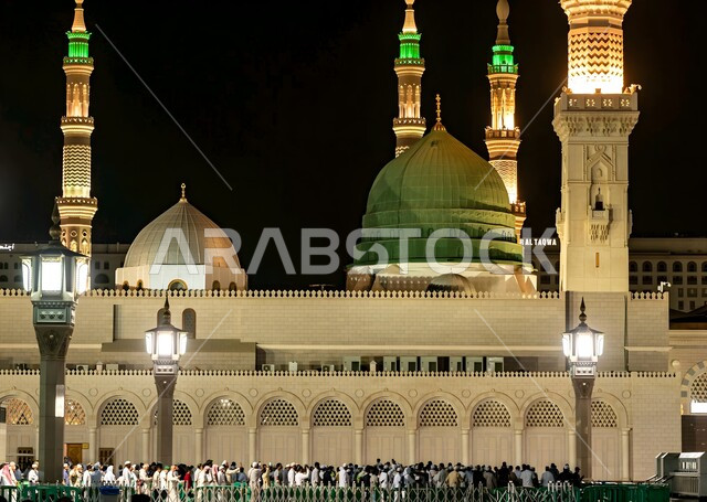 القبة الخضراء والمآذن الشامخة المضيئة ليلا، المسجد النبوي الشريف في المدينة المنورة بالمملكة العربية السعودية، المعالم الدينية الإسلامية المشهورة، تجمع المسلمين في المجمع الخارجي للحرم النبوي, الأماكن المقدسة في الدين الإسلامي