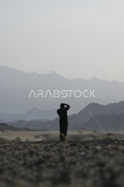 التشكيلات والتكوينات والكثبان الرملية, المساحات الواسعة في صحاري المملكة العربية السعودية, الرمال الذهبية الناعمة في الصحراء, صورة من الخلف لرجل عربي خليجي سعودي يرتدي الزي الكاجوال يحمل بيده كاميرا فوتوغرافية ويقوم بتصوير الطبيعة الصحراوية