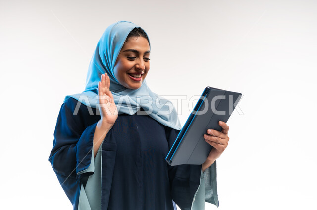 دمج التكنولوجيا الحديثة في الحياة اليومية، إلقاء التحية والترحيب والسلام، بورتريه مقرب لامرأة عربية خليجية عمانية ترتدي العباءة تقوم بإجراء مكالمة فيديو، شابة سعودية تستخدام جهاز التابلت، التواصل مع الأهل والأصدقاء، خلفية بيضاء