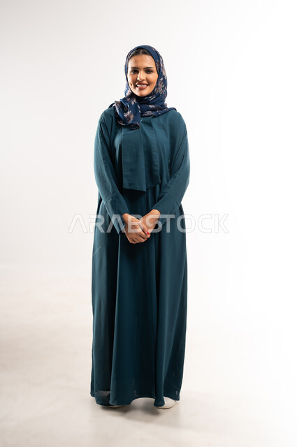 الاهتمام بالمظهر الخارجي، مفهوم الأناقة والأنوثة, بورتريه لامرأة عربيه عمانية محجبة ترتدي العباءه تقف باستقامة واعتدال بايماءات الثقة بالنفس, التقاط صور شخصية للوثائق الرسمية، سيدة سعودية تنظر إلى الكاميرا بتعابير السعادة، الطول الكامل للجسم, خلفية بيضاء