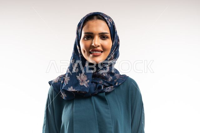 مفهوم الأناقة والأنوثة, بورتريه مقرب لامرأة عربيه عمانية مبتسمة محجبة ترتدي العباءه تقف باستقامة واعتدال بايماءات الثقة بالنفس, التقاط صور شخصية للوثائق الرسمية، سيدة سعودية تنظر إلى الكاميرا بتعابير السعادة والسرور، الاهتمام بالمظهر الخارجي، خلفية بيضاء