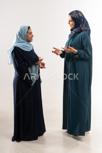 تعابير الصداقة العميقة, ايماءات السعادة والسرور، مناقشات وحوارات بين سيدات الأعمال السعودية، بورتريه لامرأتين عربيتين خليجيتين عمانيتين ترتديان العباءة تقومان بتبادل الخبرات والمعلومات الناجحة, التعاون والتفاهم بين الفريق, الطول الكامل للجسم، خلفية بيضاء
