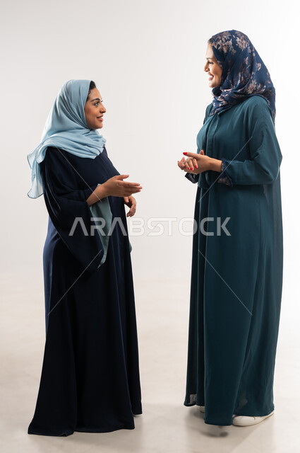 تعابير الصداقة العميقة, ايماءات السعادة والسرور، مناقشات وحوارات بين سيدات الأعمال السعودية، بورتريه لامرأتين عربيتين خليجيتين عمانيتين ترتديان العباءة تقومان بتبادل الخبرات والمعلومات الناجحة, التعاون والتفاهم بين الفريق, الطول الكامل للجسم، خلفية بيضاء
