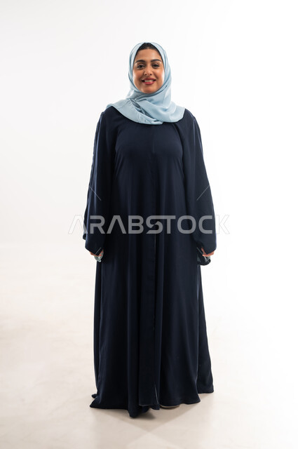 Taking selfies for official documents, Saudi woman looking at camera with happy expression, interest in appearance, concept of elegance and femininity, portrait of veiled Omani Arab woman wearing abaya standing straight and upright with self-confident gestures, full body length, white background