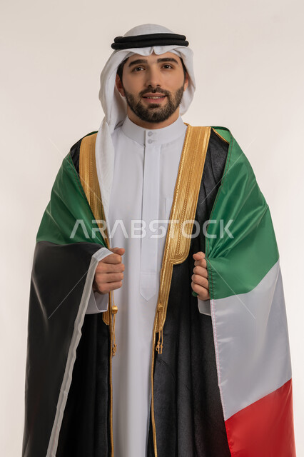 استذكار اليوم الوطني الكويتي في 25 فبراير, مناسبات وأعياد وطنية, اظهار مشاعر الفخر بالانتماء للوطن, بورتريه لشاب عربي خليجي كويتي يرتدي الدشداشة الكويتية والبشت يضع على كتفه علم دولة الكويت باعتزاز, خلفية بيضاء