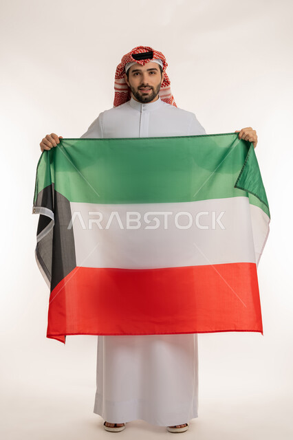 اظهار مشاعر الفخر بالانتماء للوطن, الاحتفال بالمناسبات والأعياد الوطنية, بورتريه لشاب عربي خليجي كويتي يرتدي الثوب التقليدي والشماغ ينظر إلى الكاميرا باعتزاز, استذكار اليوم الوطني الكويتي في 25 فبراير, الاخلاص والولاء للبلاد، الجسم بالطول الكامل، خلفية بيضاء