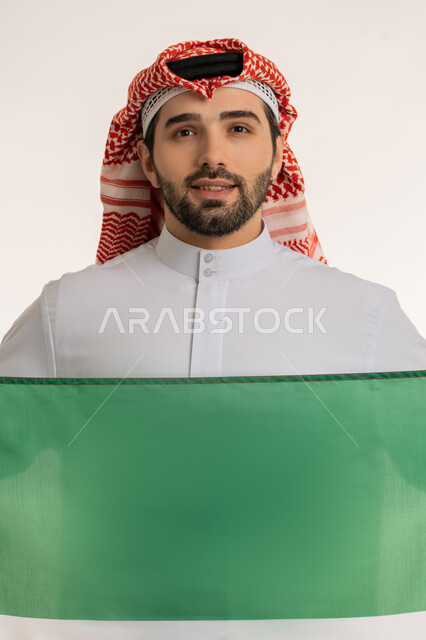 الاحتفال بالمناسبات والأعياد الوطنية, اظهار مشاعر الفخر بالانتماء للوطن, بورتريه لشاب عربي خليجي كويتي يرتدي الثوب التقليدي والشماغ ينظر إلى الكاميرا باعتزاز, استذكار اليوم الوطني الكويتي في 25 فبراير, الاخلاص والولاء للبلاد، خلفية بيضاء