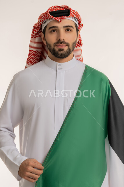 الاحتفال بالمناسبات والأعياد الوطنية, اظهار مشاعر الفخر بالانتماء للوطن, بورتريه لشاب عربي خليجي كويتي يرتدي الثوب التقليدي والشماغ ينظر إلى الكاميرا باعتزاز, استذكار اليوم الوطني الكويتي في 25 فبراير, الاخلاص والولاء للبلاد، خلفية بيضاء