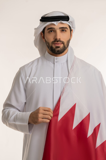 Celebrating Qatar National Day December 18, commemorating the founding of the state, close-up portrait of a Qatari Gulf Arab man holding the Qatari flag on his shoulder with gestures of pride and honor, national symbols and cultures, love of the homeland and belonging to it, white background