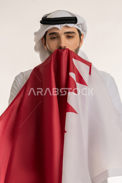الاحتفال باليوم الوطني القطري 18 ديسمبر، إحياء ذكرى تأسيس الدولة، بورتريه مقرب لرجل عربي خليجي قطري يحمل علم قطر ويقوم بتقبيله بايماءات الفخروالاعتزاز، رموز وثقافات وطنية, حب الوطن والانتماء إليه، خلفية بيضاء