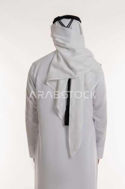 مفهوم الأناقة والرجولة, الاهتمام بالمظهر الخارجي, بورتريه من الخلف لرجل عربي خليجي سعودي يرتدي الثوب التقليدي والغترة يقف باستقامة واعتدال, خلفية بيضاء