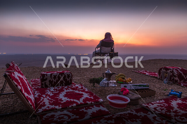التكوينات والتشكيلات الصخرية والمناظر الطبيعية في الصحراء، حافة نهاية العالم الجبلية في مدينة الرياض في المملكة العربية السعودية ، المعالم والأماكن السياحية الطبيعية المشهورة ، صورة لرجل عربي سعودي يرتدي الثوب والشماغ يجلس على كرسي مريح