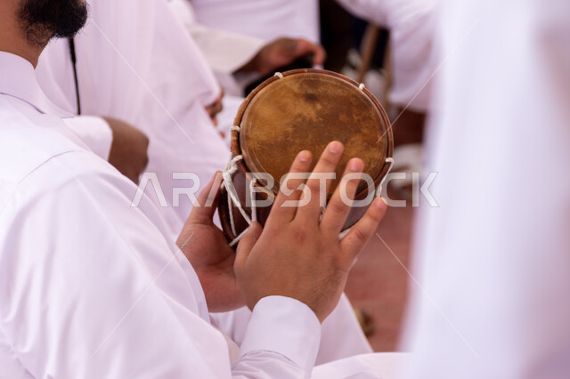 Folk arts and shows, dances on national occasions, festivals and holidays in Qatar, events and celebrations for shows and arts, old heritage neighborhoods, a Saudi Arabian Gulf Ardah band wearing traditional dress and ghutra celebrating and beating drums