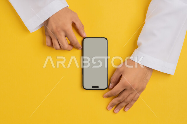 التسويق الالكتروني للتطبيقات، عرض شاشة رمادية فارغة، دمج التكنولوجيا الحديثة في الحياة اليومية والعملية، بورتريه علوي عامودي لايدي رجل عربية خليجي سعودي يقوم بتقديم خدمات الموبايل، شاب اماراتي يستخدام الهاتف المحمول، خلفية صفراء