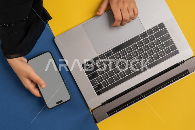 عرض شاشة رمادية فارغة، دمج التكنولوجيا الحديثة في الحياة العلمية والعملية، التسويق والترويج للمواقع الالكترونية، بورتريه علوي عامودي لايدي امرأة عربية خليجية اماراتية تحمل الهاتف المحمول، شاب سعودي يستخدام الحاسوب المحمول، خلفية ملونة