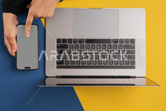 عرض شاشة رمادية فارغة، دمج التكنولوجيا الحديثة في الحياة العلمية والعملية، التسويق والترويج للمواقع الالكترونية، بورتريه علوي عامودي لايدي امرأة عربية خليجية اماراتية تقوم بالنقر على الهاتف المحمول، شاب سعودي يستخدام الحاسوب المحمول، خلفية ملونة