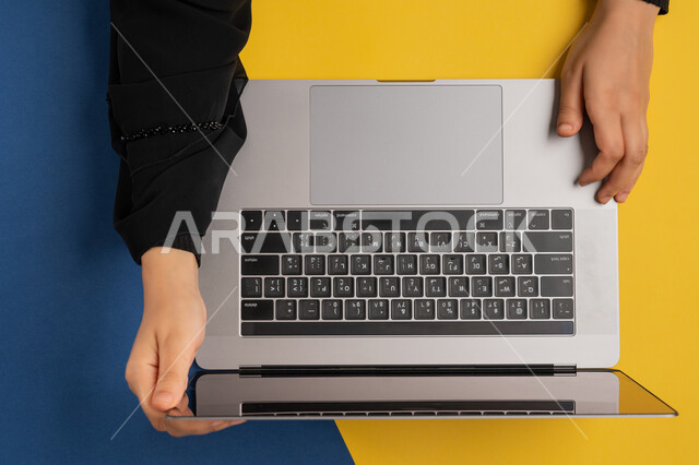 مفهوم ادارة الاعمال وتحقيق الأهداف، دمج التكنولوجيا الحديثة في الحياة العملية، إنجاز المهام المطلوبة عن بعد، بورتريه علوي عامودي لايدي امرأة عربية خليجية اماراتية تعمل على اللابتوب، شابة سعودية ترتدي العباءة تحمل جهاز الحاسوب المحمول، خلفية ملونة
