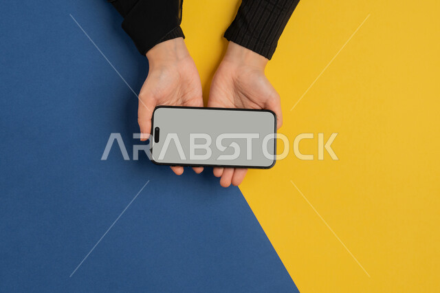 عرض شاشة رمادية فارغة، التسويق الالكتروني للتطبيقات، دمج التكنولوجيا الحديثة في الحياة اليومية والعملية، بورتريه علوي عامودي لايدي امرأة عربية خليجية سعودية تقوم بتقديم خدمات الموبايل، شابة اماراتية تستخدام الهاتف المحمول، خلفية ملونة