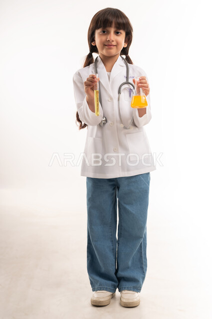 اجراء تجارب وتفاعلات كيميائيه حيويه، بورتريه لفتاة عربية خليجية عمانية ترتدي المعطف وتحمل انابيب الاختبار، بنت سعودية تقوم بأبحاث علمية في معمل الكيمياء، أمنية الحصول على مهنة الباحثة الكيميائية، تحديد المهنة المستقبلية منذ الصغر، الطول الكامل للجسم، خلفية بيضاء