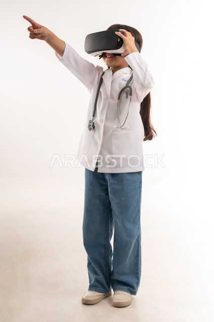 Integration and simulation of the virtual world, hopes for his future in working in hospitals, portrait of a smiling Gulf Arab Omani girl wearing a coat and stethoscopes, a Saudi girl wearing 3D glasses, technical and technological development in the field of medicine, full body length, white background
