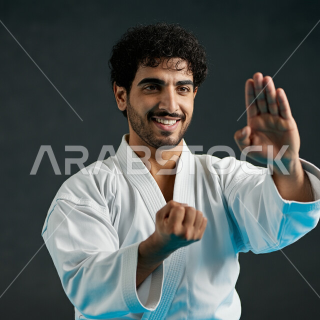 احتراف المهارات القتالية الخاصة، الاهتمام برياضة الكاراتيه في السعودية، بورتريه مقرب لشاب عربي خليجي سعودي يرتدي الزي الأبيض المخصص ذو الحزام ويقوم بالتدرب على الحركات، رياضات الألعاب الأولمبية، الانضمام لنادي رياضي والمشاركة في المنافسات العالمية، خلفية سوداء