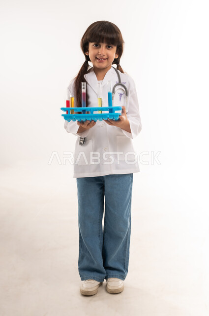 الشغف بالحصول على مهنة الباحثة الكيميائية، اجراء تجارب وتفاعلات كيميائيه حيويه، بورتريه لفتاة عربية خليجية عمانية ترتدي المعطف وتحمل انابيب الاختبار، بنت سعودية تقوم بأبحاث علمية في معمل الكيمياء، تحديد المهنة المستقبلية منذ الصغر، الطول الكامل للجسم، خلفية بيضاء