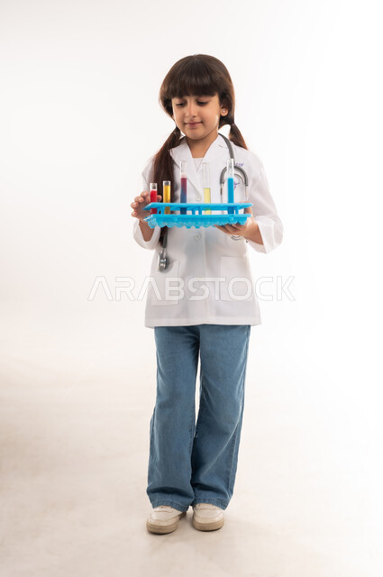 اجراء تجارب وتفاعلات كيميائيه حيويه، بورتريه لفتاة عربية خليجية عمانية ترتدي المعطف وتحمل انابيب الاختبار، بنت سعودية تقوم بأبحاث علمية في معمل الكيمياء، أمنية الحصول على مهنة الباحثة الكيميائية، تحديد المهنة المستقبلية منذ الصغر، الطول الكامل للجسم، خلفية بيضاء
