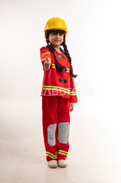 Volunteering in rescue teams and loving to help people, striving to achieve childhood dreams in the future, portrait of an Arab Gulf Omani girl wearing a protective vest and helmet raising her thumb with expressions of admiration and acceptance, a Saudi girl looking at the camera with gestures of happiness, full body length, white background
