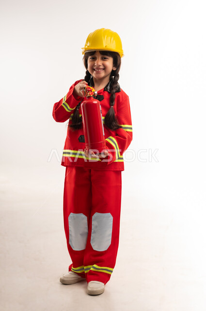 Love to help people and volunteer in rescue teams, striving to achieve childhood dreams and wishes in the future, portrait of a smiling Gulf Arab Omani girl wearing a protective vest and helmet holding a fire extinguisher in her hand, Saudi girl looking at the camera with gestures of happiness, full body length, white background