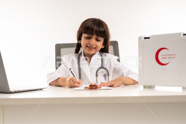 الأهداف والطموحات المستقبلية بالعمل في العيادات والمشافي، تدوين نتائج الفحوصات بالسجل الطبي، بورتريه لبنت عربية خليجية عمانية ترتدي المعطف الأبيض، فتاة سعودية تجلس امام الطاولة تقوم بإعداد التقارير الطبيه وبجانبها الحاسوب المحمول، تحديد مهنة المستقبل، خلفية بيضاء