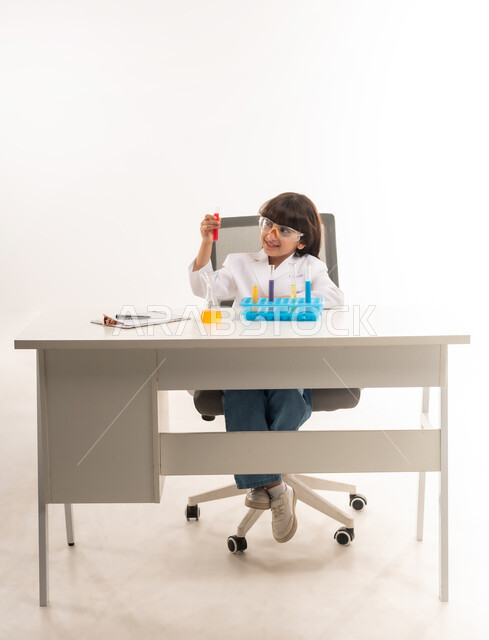 اجراء تجارب وتفاعلات كيميائيه حيويه في المختبر، بورتريه لفتاة عربية خليجية عمانية ترتدي معطف أبيض وتستخدم انابيب الاختبار، بنت سعودية تقوم بأبحاث علمية في معمل الكيمياء، أمنية الحصول على مهنة الباحثة الكيميائية، اختيار وتحديد المهنة المستقبلية منذ الصغر، خلفية بيضاء